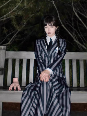 Spot Wednesday Cosy Clothes featuring a black and gray vertical striped dress with a blazer and tie, worn with dark braided hair and gothic makeup.