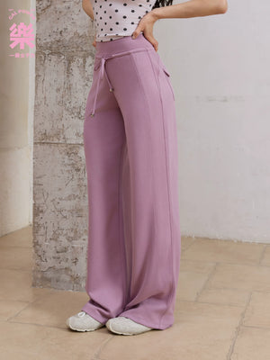 Model wearing purple straight leg sweatpants with polka dot top, side view