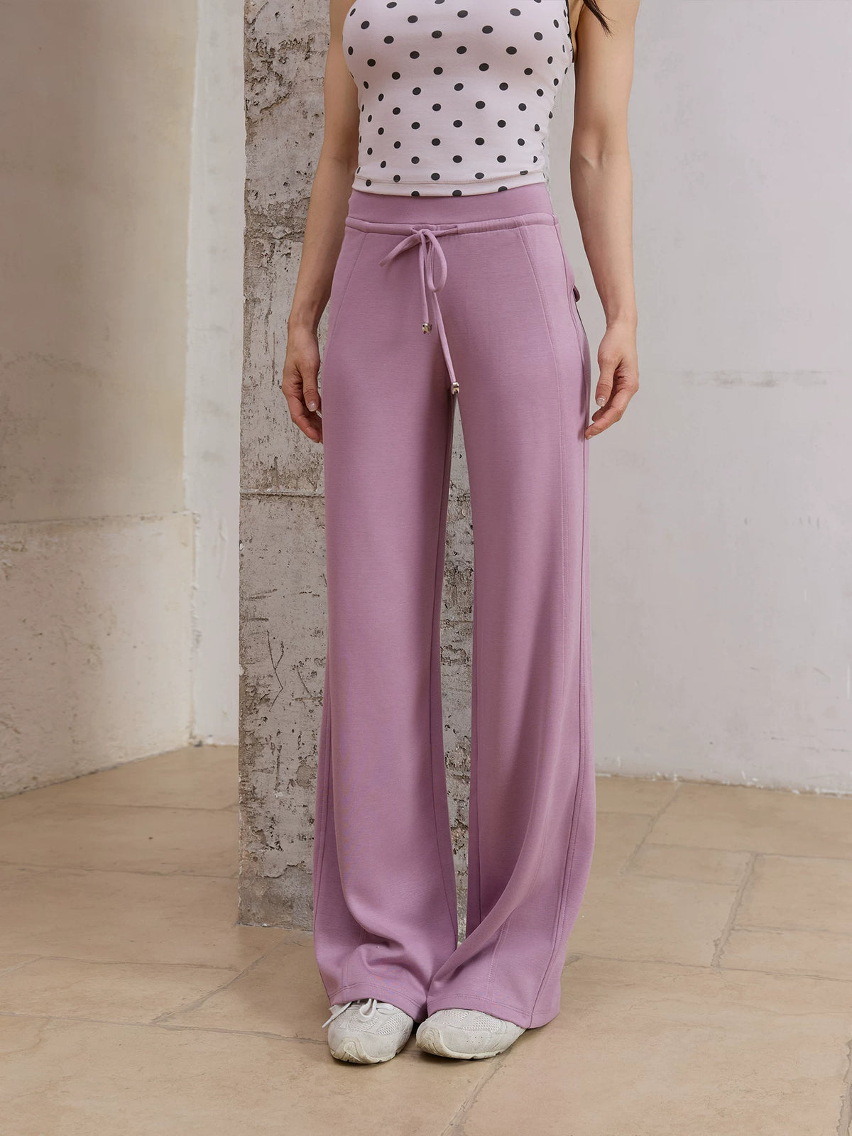 Model wearing purple straight leg sweatpants with polka dot top, front view