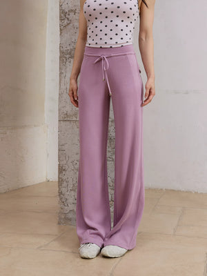 Model wearing purple straight leg sweatpants with polka dot top, front view