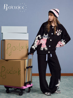 Model wearing the black coral fleece loungewear set with pink and white hat, full body front view