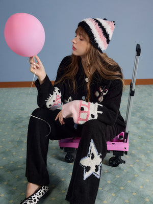 Model wearing the black loungewear set sitting with pink balloon, side view