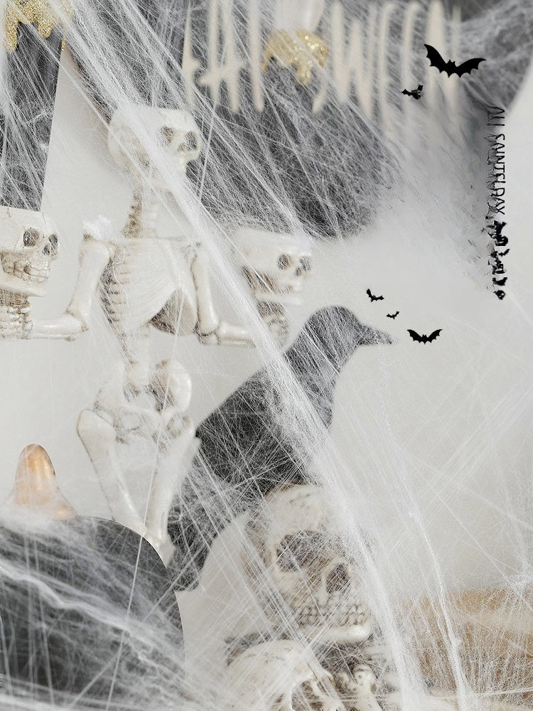 Halloween decorations featuring white synthetic spider webs, plastic skeletons, and skulls arranged in a spooky haunted house scene.